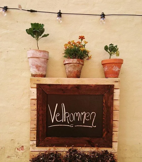 Velkommen-skilt og urtepotter i Bistroens gårdhave